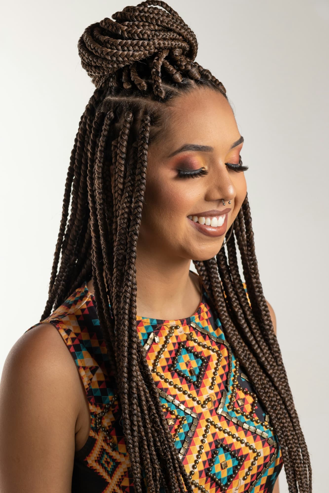 Femme souriante aux box braids relevées en chignon