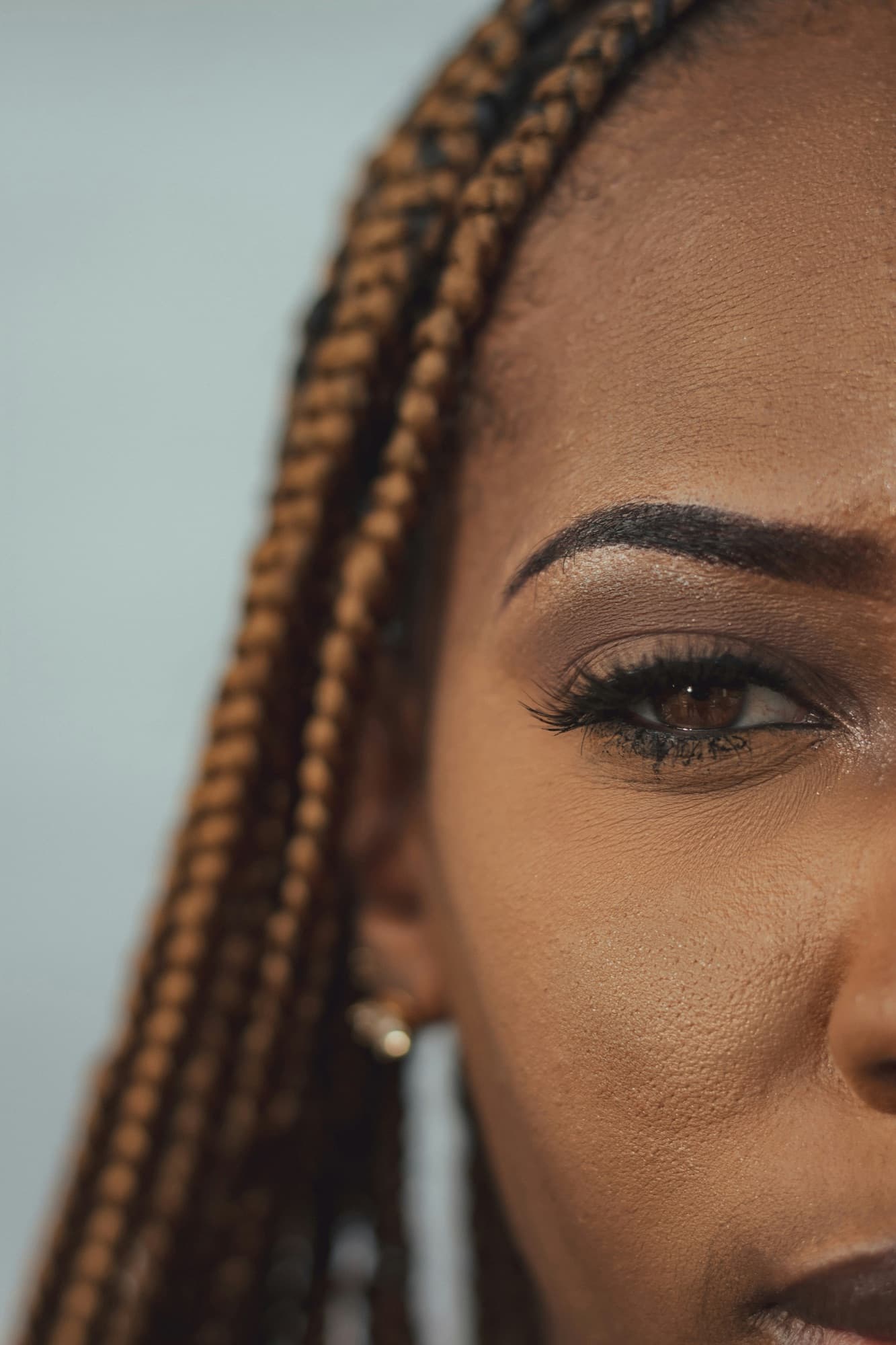 Gros plan sur un œil maquillé, des cils et des tresses